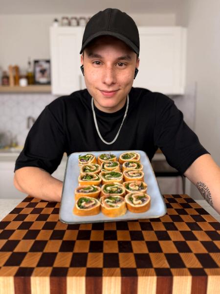 Théo lignani in a black hat holds a tray of food