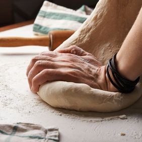 une personne pétrit de la pâte sur une table avec un rouleau à pâtisserie