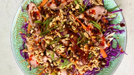 Asian noodle salad with sliced duck, purple cabbage, carrots, green onions, and peanuts.