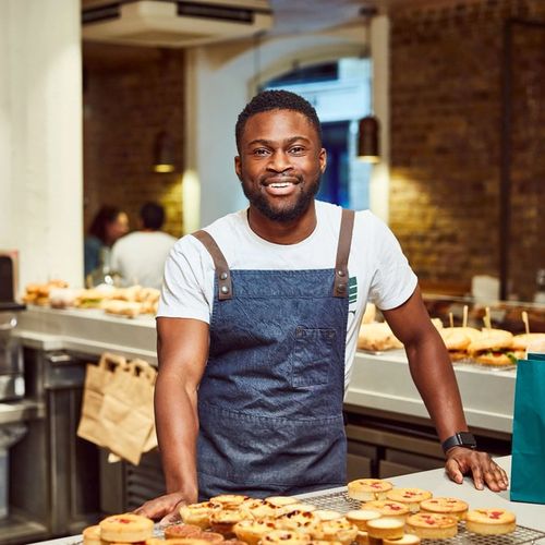 a man is standing behind a counter holding a bag of food .