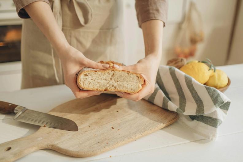 a woman is holding a loaf of bread in her hands on a cutting board.