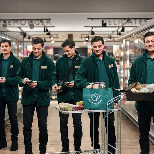 four men wearing green jackets are standing in front of a sign that says delicates