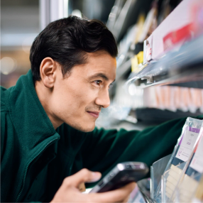 a man in a green jacket is holding a tray of vegetables