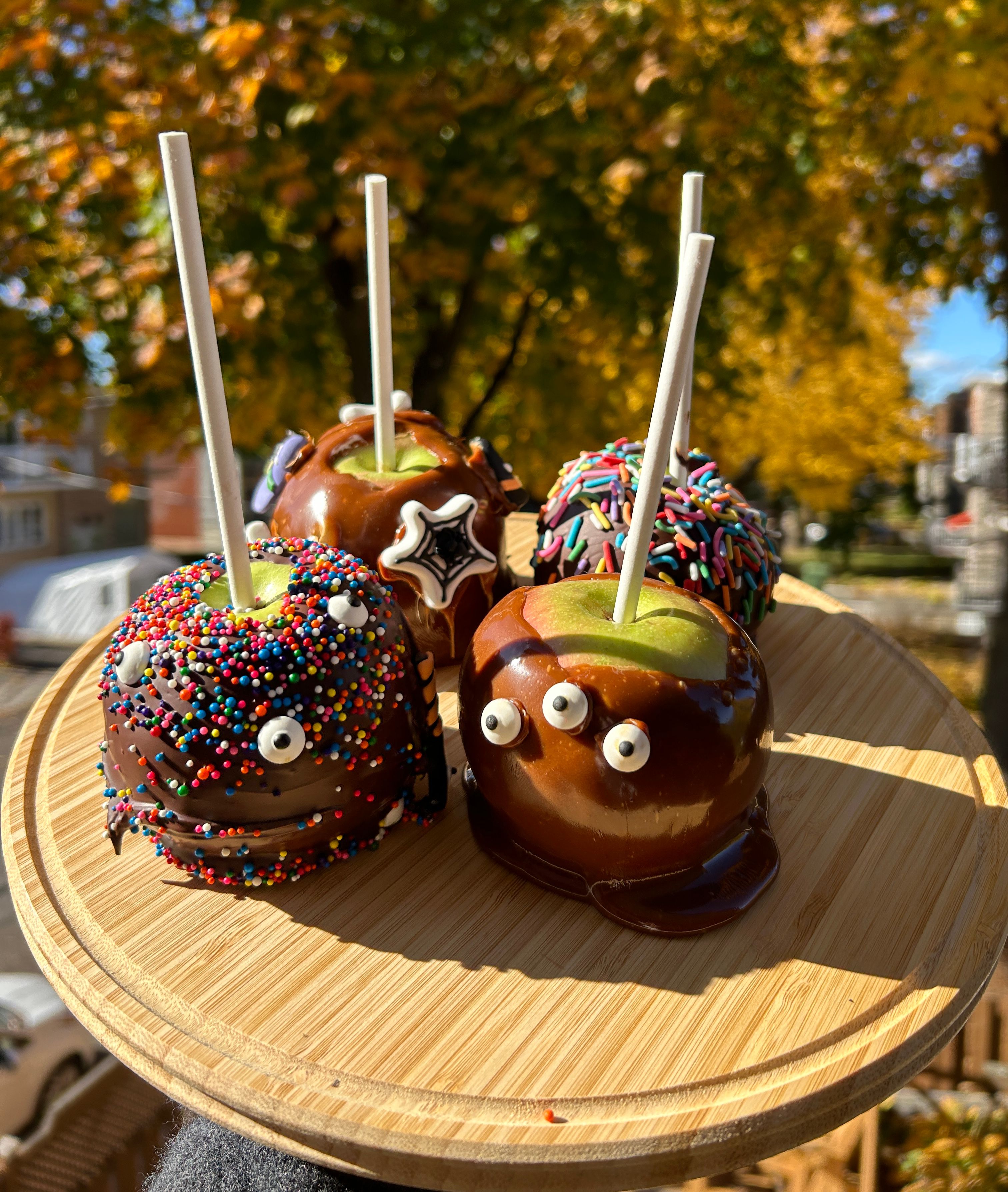 a wooden cutting board with four caramel apples on it