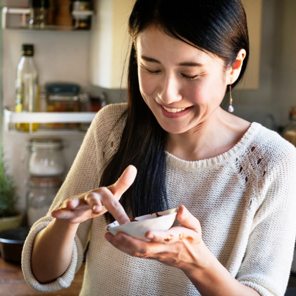 a woman in a white sweater is holding a small white bowl