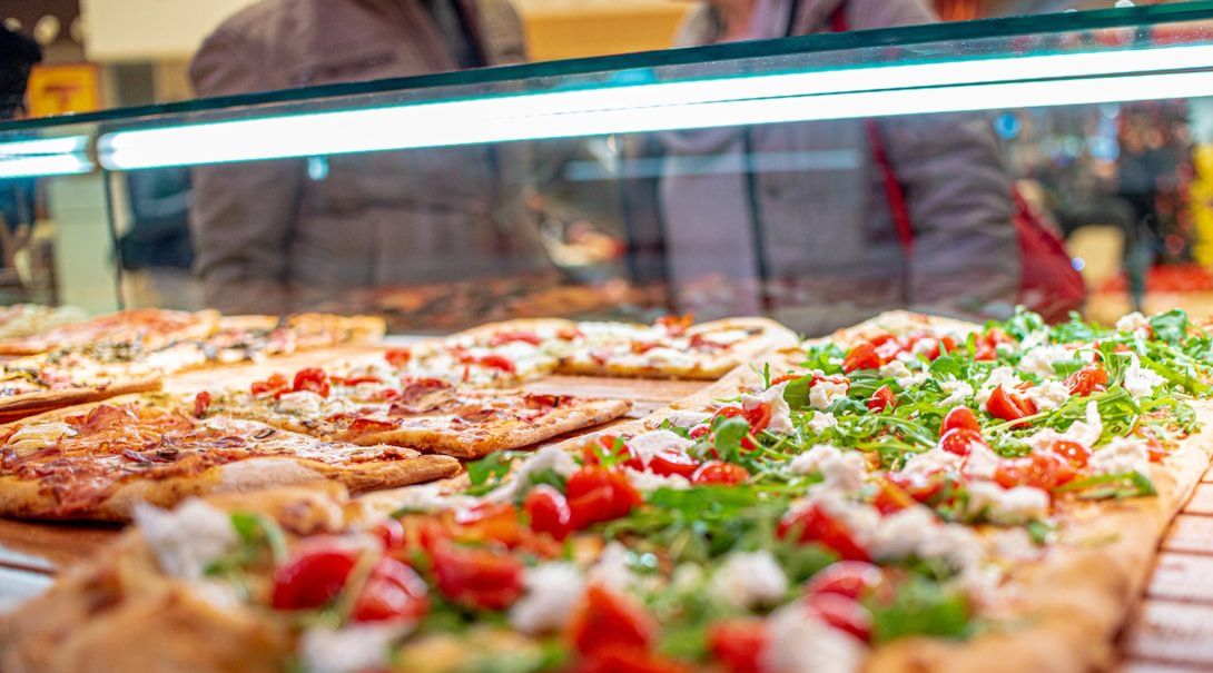 a display case filled with lots of different types of pizzas .