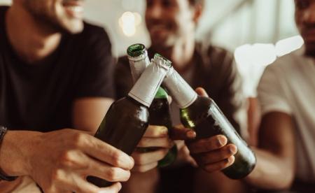 a group of men are toasting with beer bottles .