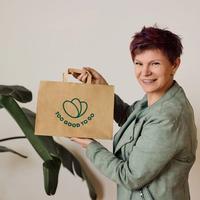 a woman in a green suit and white shirt is standing in front of a plant .