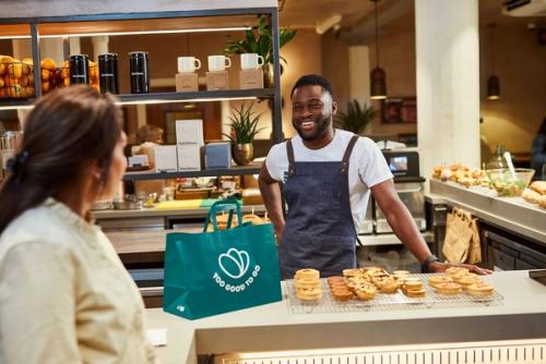 a man is standing behind a counter in a bakery talking to a woman .