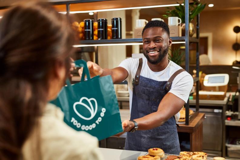 a man is giving a bag to a woman in a bakery .