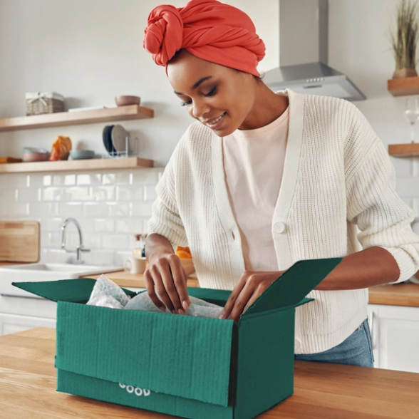 a woman in a red turban is opening a green box that says good