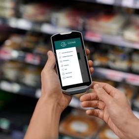 a person is holding a cell phone in a grocery store .