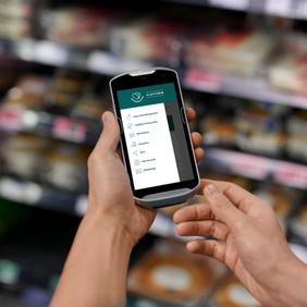 a person is holding a cell phone in a grocery store .