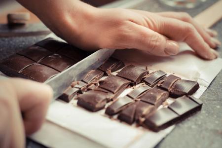 a person is cutting a bar of chocolate into pieces .