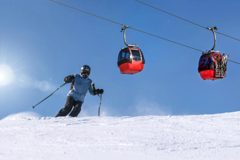 a man is skiing down a snow covered slope next to a ski lift .