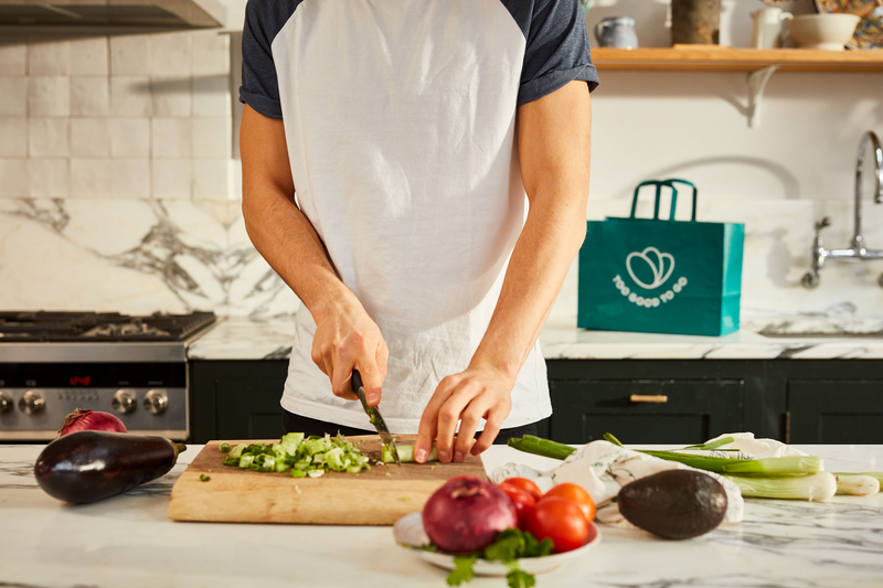 a man is cutting up vegetables in a kitchen with a bag that says " good food to go "