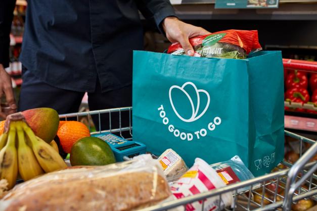 a person is putting a bag of food in a shopping cart .