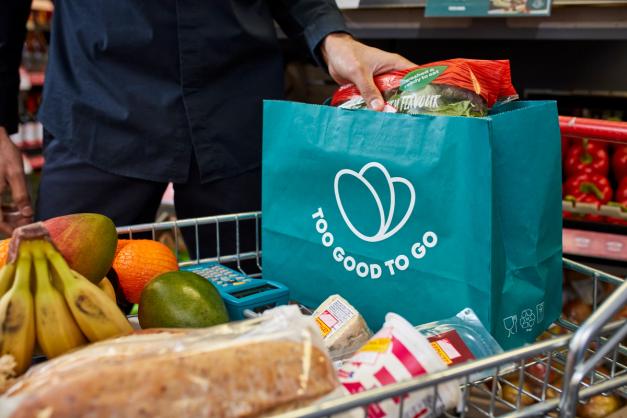 a person is putting a bag of food in a shopping cart .