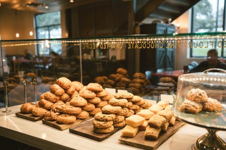 a display case filled with a variety of pastries and cookies in a bakery .