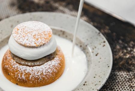 a close up of a semla on a plate with milk being poured on it 