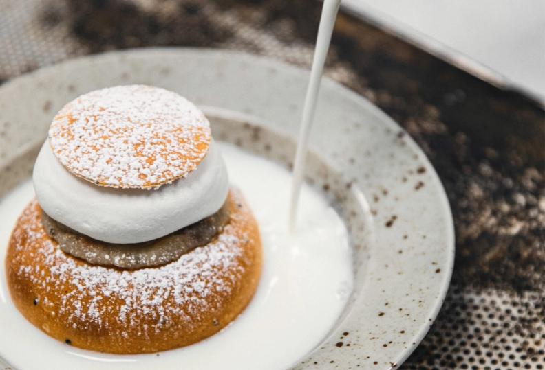 a close up of a semla on a plate with milk being poured on it 