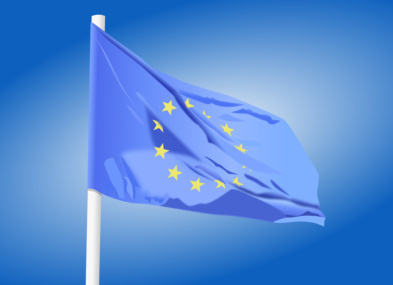 a the european flag blue with yellow stars on it is flying in the wind against a blue sky 