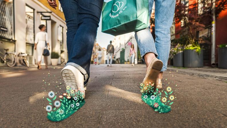 a couple of people are walking down a sidewalk with a Surprise Bag from Too Good To Go 