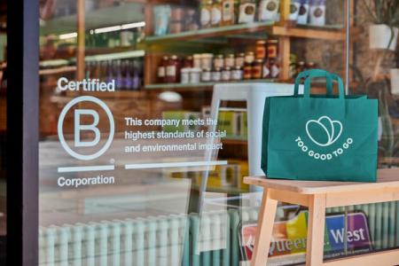 a green bag is sitting on a wooden stool in front of a store window .