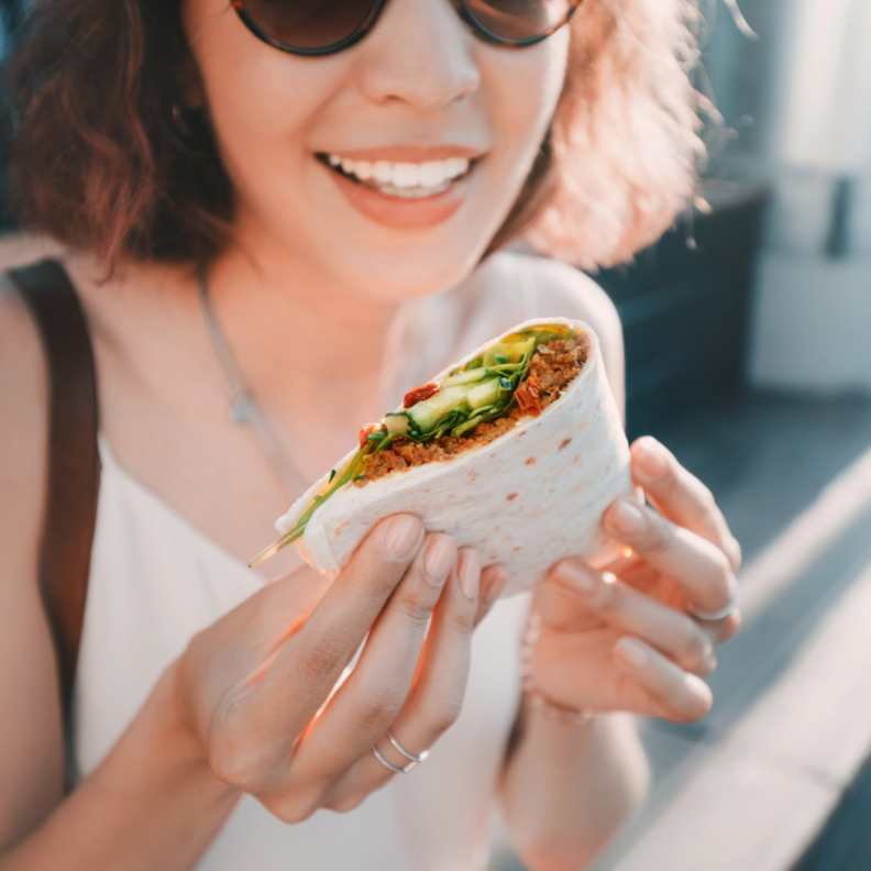 Woman in sunglasses holding a quesadilla 