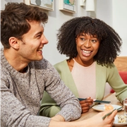 a man and a woman are sitting at a table with plates of food and chopsticks