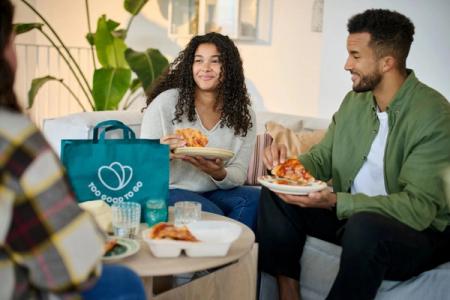 a group of people are sitting on a couch eating pizza .