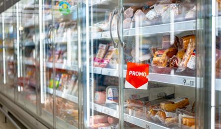 Supermarket refrigerated display case filled with packaged meats, featuring a red "PROMO" sign.