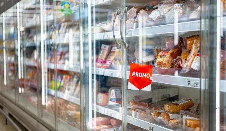 Supermarket refrigerated display case filled with packaged meats, featuring a red "PROMO" sign.
