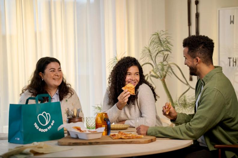 a group of people are sitting at a table eating pizza.
