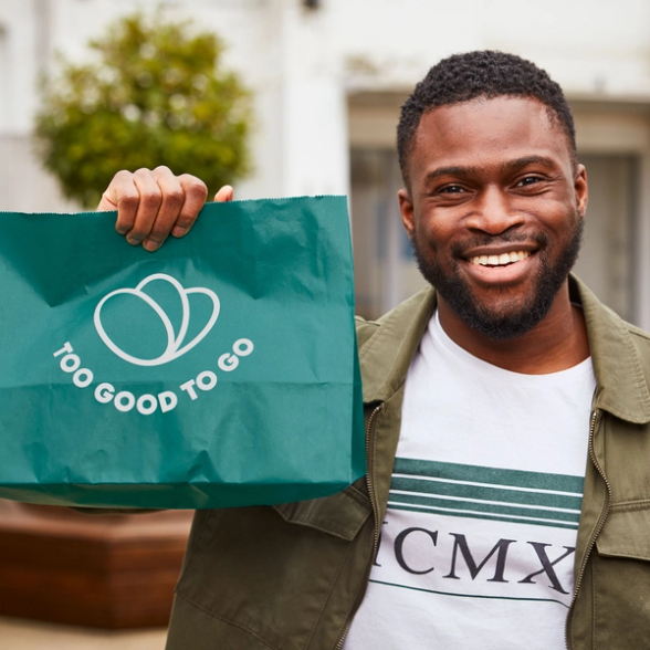 a man holding a green bag that says too good to go