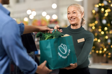 a woman is holding a bag that says too good to go