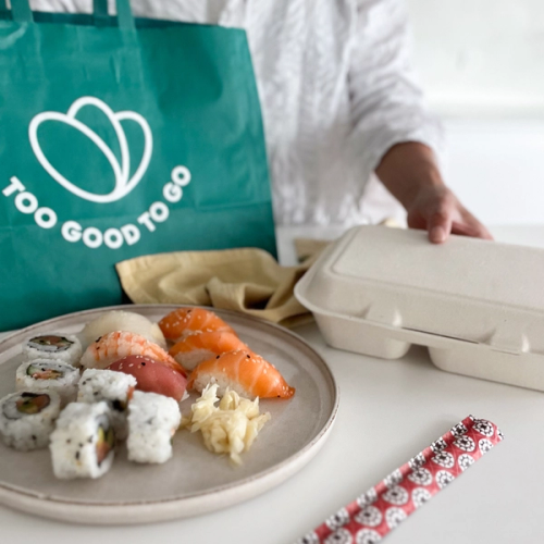 a plate of sushi next to a bag that says too good to go