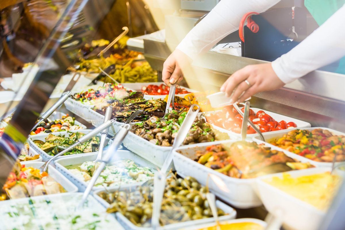 an assortment of foods in trays displayed in a counter with spoons