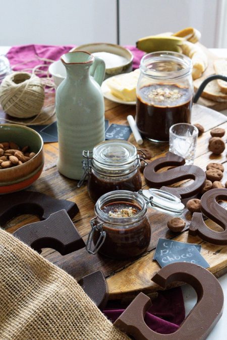 a jar of chocolate sauce sits on a wooden table