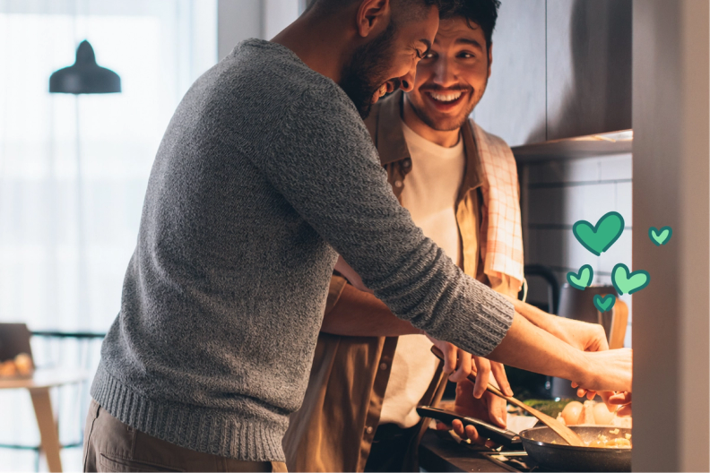 Two happy men cooking in a kitchen, with green hearts.