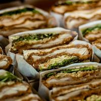 cut sandwiches containing greens and meat wrapped in paper