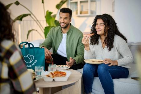 Un hombre y una mujer en un sofá comiendo pizza de un Pack Sorpresa