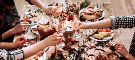Overhead view of a festive dining table set with a greenery centerpiece, lit candles, multiple food dishes, and place settings.