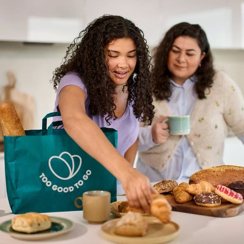 two women are standing in a kitchen preparing food .