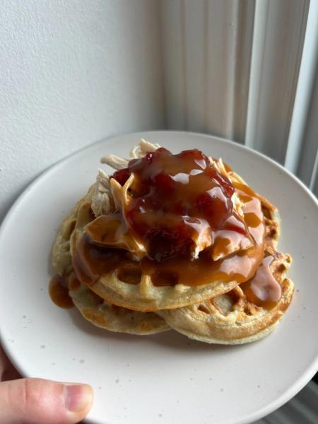 a person is holding a plate of waffles with gravy on top