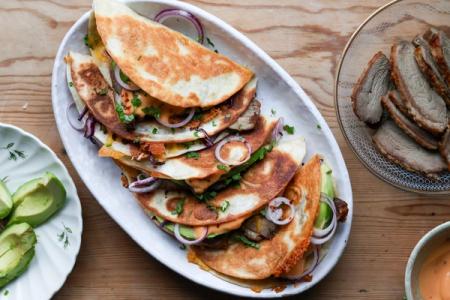 a white plate topped with quesadillas and avocado on a wooden table .