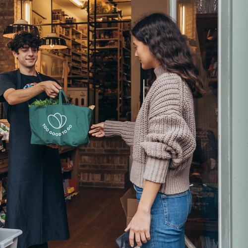 a man is giving a green bag to a woman in a store .