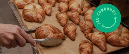 a person is cutting a croissant with a pair of tongs on a tray of croissants .