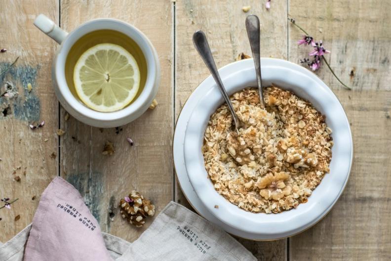 a bowl of oatmeal and a cup of tea on a wooden table .