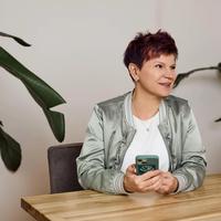 a woman is sitting at a table holding a cell phone .